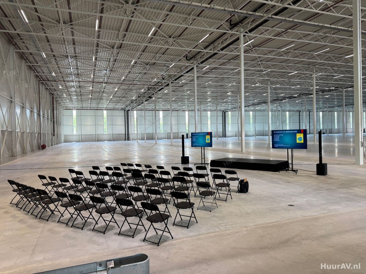 Bedrijfsevenement met een verlicht podium, publiek en verzorgde presentatietechniek in een zaal