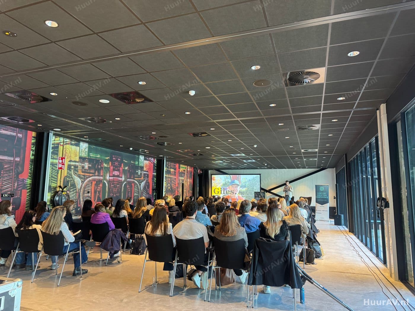 Zaal tijdens een zakelijke presentatie met verlicht podium en groot scherm